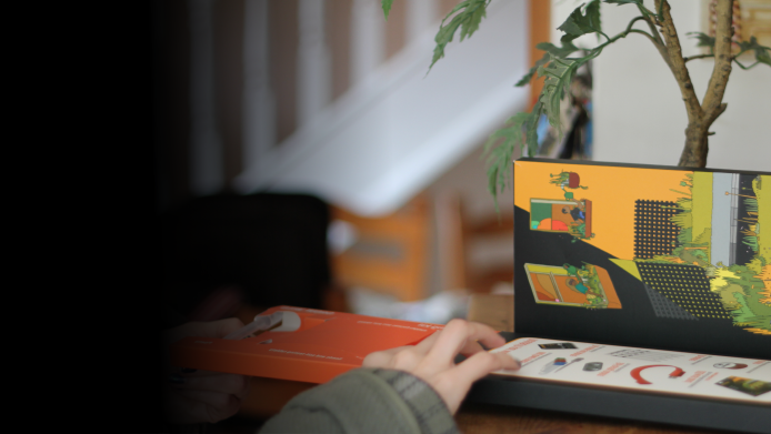 Someone opens a Grow Wild wildflower seed kit on a wooden table