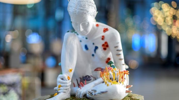 A statue of a person, covered in colourful fungi
