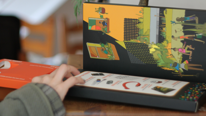A hand touching an open black box with graphics on the inside of the lid 